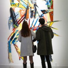 Gallery visitors viewing a laser-cut painting by Jason Baerg.