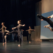 a group of dancers in plain clothes rehearse a ballet performance on stage