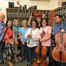Musicians from Livington Symphony Orchestra in a rehearsal space holding their instruments
