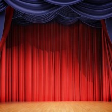 an image of blue stage curtains pulled back to reveal a red stage curtain
