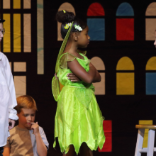 children in Wendy and Tinkerbell costumes share a scene in a production of Peter Pan Jr