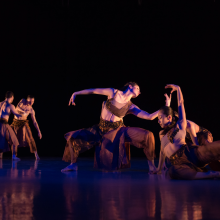 A group of dancers on stage in a dark room