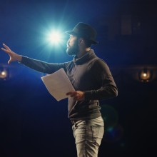 an actor holding his script performing in front of a spotlight