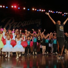A group of kids posing on stage in dance costumes