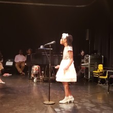 A young girl singing on stage