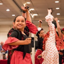 A group of people, young and old, dancing in red and white Flamenco attire