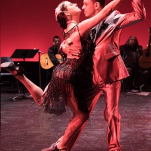 A man and woman dancing on stage under red lights
