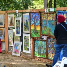 a couple of people admiring some landscape art up on display grids