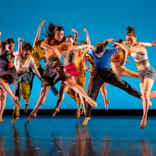 Group of dancers jumping with feet off the stage