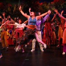 Large group of people in colorful costumes singing and dancing