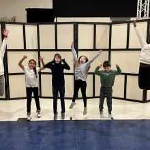 A group of kids jumping in the air as part of a theatre exercise