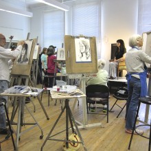 Adult students with easels drawing a model
