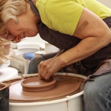 Adult Student sitting at a pottery wheel.