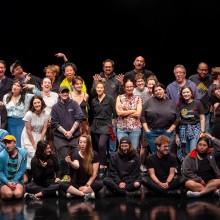 A group of people on a darkened stage posing for a photo.