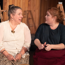 Two women sitting on a stage talking to each other