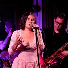 A singer performing live on stage at the Lizzie Rose Music Room