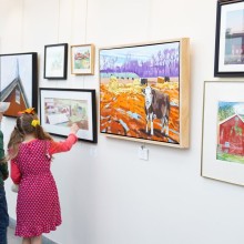 Two children looking at paintings on a wall.