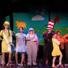 Cast of actors dress colorfully onstage.