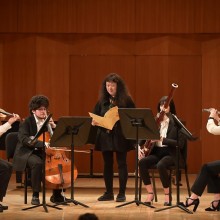 Five musicians playing instruments onstage.