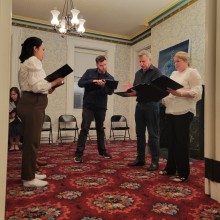 A group of people standing in a room holding music books.