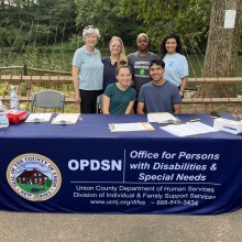 Group of people pose in front of a Union County Division of Cultural & Heritage Affairs marketing table.