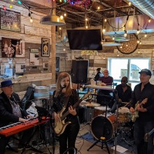 A group of people playing music in a bar with wooden walls