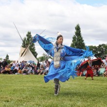 An Indigenous woman dancing at an outdoor festival
