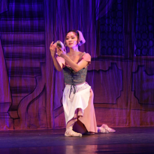 Ballerina in peasant ware kneeling onstage.