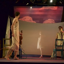 Actors from PST performing on a stage with a fabric wall divider