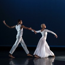 A pair of dancers wearing white costumes on a stage.