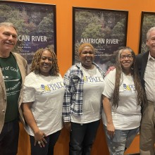 A group of people in matching shirts standing in front of posters