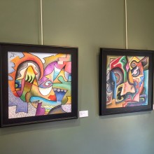 Two colorful paintings hanging on a green wall