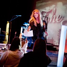 Woman performer handing a paper to audience member from the stage.