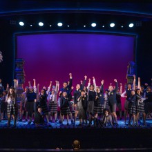 A group of people standing on a stage with their hands raised
