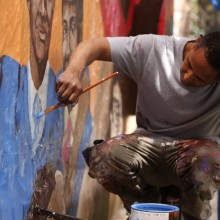 A muralist painting from a scaffold.