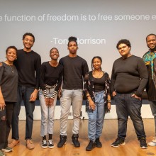 A group of people pose for a picture in front of a projection.