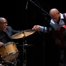 a drummer and a bassist shake hands