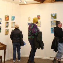 3 people are viewing art on the wall of a gallery