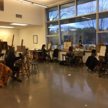 students in a classroom working at easels
