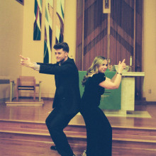 a male and female performer are on stage back to back holding their hands as if the are holding a pistol