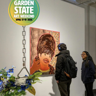 Visitors view a colorful portrait painting in a gallery beneath a hanging “Garden State Art Weekend” sign.