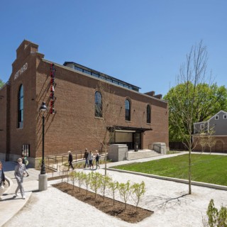 the outside of the ArtYard building, a church-like brown brick building arched windows and a neat square of grass out front