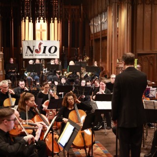 Orchestra performs in a church under the guidance of their conductor