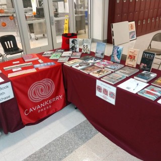 a table setup for CavanKerry Press at a fair, the table covered in books
