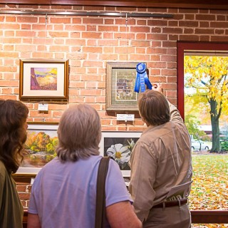 a man placing a ribbon on a painting at the Mercer County Teen Arts Festival