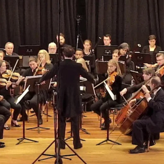 a conductor in front of a small orchestra
