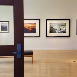 a look into an art gallery with paintings of ocean water on the walls