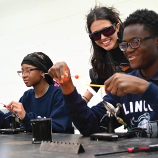Teaching Artist monitors students in a flameworking class