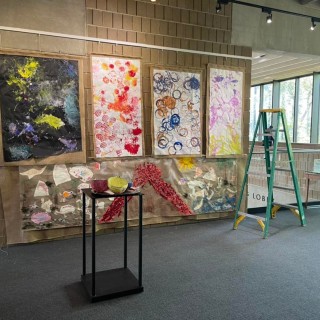 Four colorful abstract paintings hung up on the walls of an art gallery