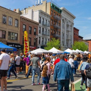 A large crowd of people passing through a street festival in Hudson County